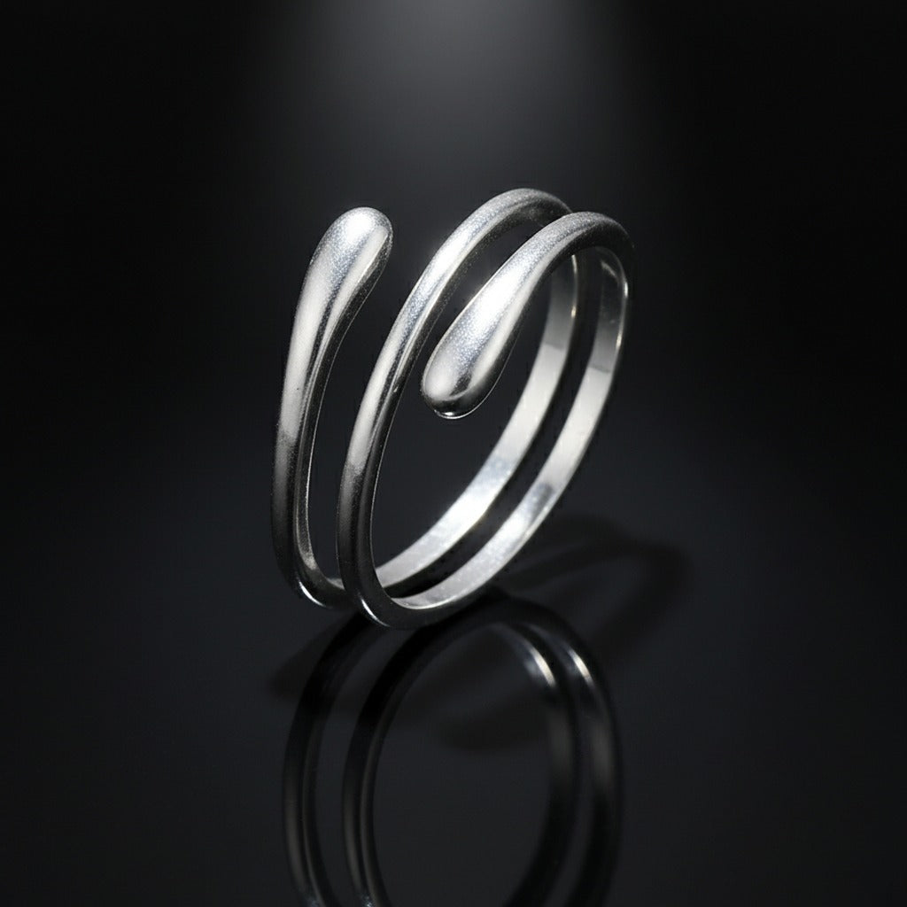 Silver spiral ring on a reflective black surface with a dark background